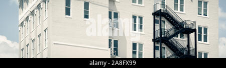 Ein Kontrast zwischen einem modernen schwarzen Iron Fire escape auf einem Vintage White Backsteingebäude in Hattiesburg, MS, USA, in einem Format Stockfoto