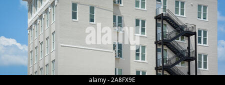 Ein Kontrast zwischen einem modernen schwarzen Iron Fire escape auf einem Vintage White Backsteingebäude in Hattiesburg, MS, USA, in einem Format Stockfoto