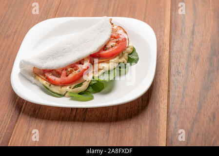 Tapioka gefüllt mit Schinken, Käse und Tomaten, auf Holz- Hintergrund. Fladenbrot aus Maniok (auch als casabe, bammy, beiju, bob, biju bekannt). Stockfoto