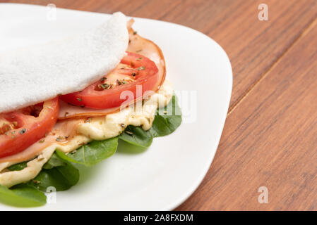 Tapioka gefüllt mit Schinken, Käse und Tomaten, auf Holz- Hintergrund. Fladenbrot aus Maniok (auch als casabe, bammy, beiju, bob, biju bekannt). Stockfoto