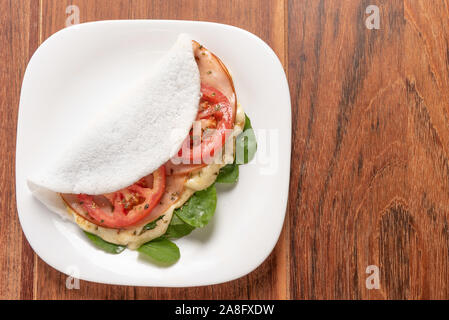 Tapioka gefüllt mit Schinken, Käse und Tomaten, auf Holz- Hintergrund. Fladenbrot aus Maniok (auch als casabe, bammy, beiju, bob, biju bekannt). Stockfoto