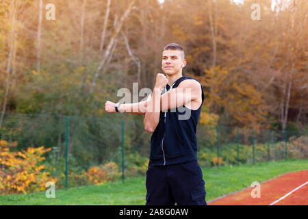 Junger Mann dehnen und Aufwärmen am Morgen im Freien auf der Rennstrecke Stockfoto