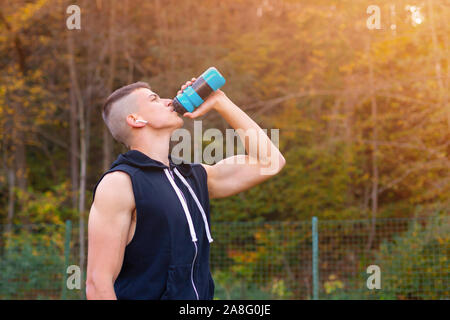 Junger Mann Trinkwasser aus der Flasche beim Joggen am Morgen außerhalb Stockfoto