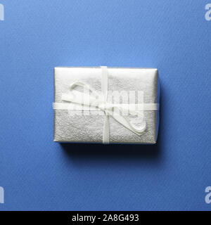 Silber Geschenkbox auf blauem Hintergrund. Weihnachten oder Geburtstag Konzept Stockfoto