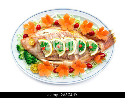 Gedünsteter Fisch (Tilapia Fisch) oben Zitronenscheibe mit geschnitzten Möhren Tomaten Gemüse Stil gesunde Lebensmittel und Ernährung Lebensmittel Draufsicht isoliert auf weißem backgrou Stockfoto