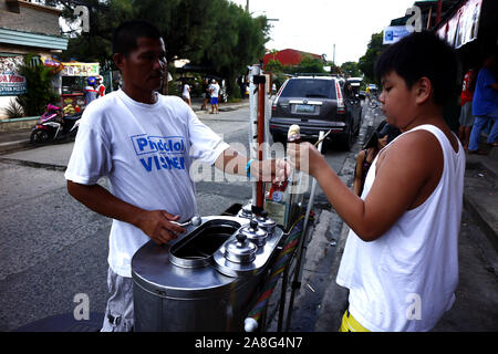 ANTIPOLO CITY, Philippinen - NOVEMBER 2, 2019: Junge Filipino junge kauft Eis von einem Eis Anbieter. Stockfoto