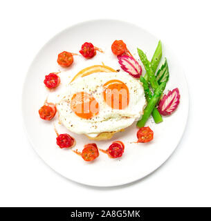 Frühstück mit gegrillten Toast auf Spiegeleier, schwarzen Pfeffer und Salz bestreuen dekorieren Tomate Kirsche, Spargel, Rettich Blatt und Gurke geschnitzten Styl Stockfoto