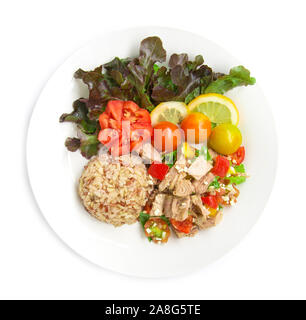 Brauner Reis mit Thunfisch Salat klare Soße gesundes Essen cleanfood Dekorieren geschnitzten Tomate, Zitrone in Scheiben schneiden und Blatt rote Eiche Top View isoliert auf weißem backgrou Stockfoto