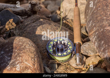 Ein Rod und Reel sitzen bereit für die Fischerei auf den Felsen entlang eines Flusses im Norden von Colorado. Stockfoto