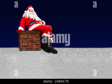 Santa Claus sitzt auf dem Schornstein an einem verschneiten Dach von Haus, Hintergrund von dunklem Blau mit Sternen. Stockfoto