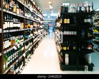 Verschwommenes Bild von Wein Regale im Supermarkt. Defokussierten Reihen von Wein Likör Flaschen im Regal. Alkoholische Getränke abstrakt Hintergrund Stockfoto