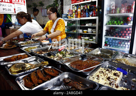 TAYTAY, Rizal, Philippinen - NOVEMBER 7, 2019: Frau serviert verschiedene warme Speisen in einem örtlichen Lokal oder Restaurant namens "Karinderia", die Zuhause Stockfoto