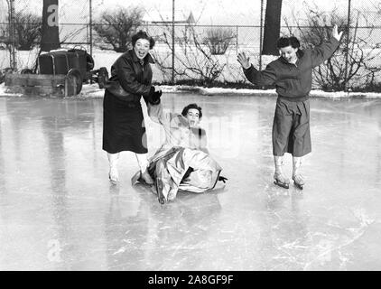 Drei Frauen haben Spaß auf dem Eis auf einem überfluteten Baseball Diamond entlang des Lake Michigan in Chicago, Ca. 1953. Stockfoto