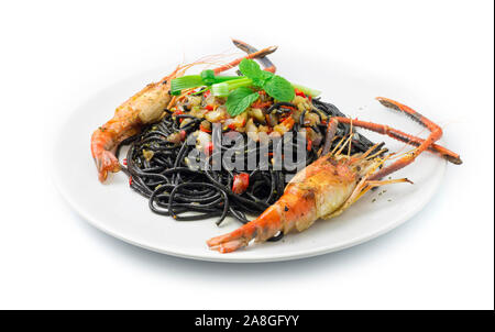 Schwarze Spaghetti scharfes Essen serviert mit gegrillten Garnelen Thai Food Gemischte italienische Fusion Style dekorieren mit geschnitzten Paprika und Frühlingszwiebeln Seitenansicht Stockfoto