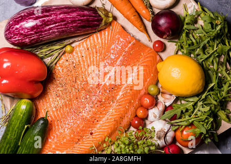 Ansicht von oben closeup große Lachsfilet, Gurken, Tomaten, Paprika, Knoblauch, Pfeffer, Zitrone, Auberginen, Möhren, Rucola, Zwiebeln auf dem Tisch Stockfoto