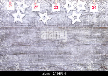 21-24 Teil der Adventskalender mit quadratischen Platten mit Zahlen auf Clips mit Schneeflocken und weiße Weihnachten Spielzeug Sterne auf weißem Holz- snowy Hintergrund Stockfoto