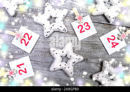 Close-up 21-24 Teil der Adventskalender mit Blätter mit Zahlen auf dekorative Clips, weiße Weihnachten Spielzeug Sterne, farbige verschwommen Lichter auf weißem Woode Stockfoto