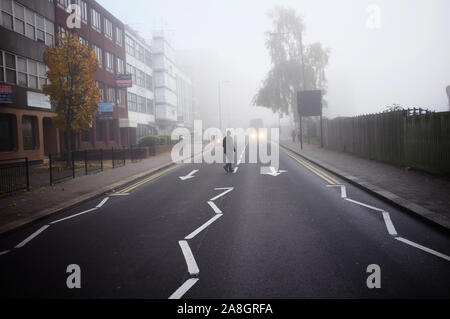 North West London, Harrow on the Hill, ein Mann über die Straße auf einem sehr Nebligen Morgen Stockfoto