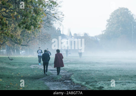 Wimbledon London, UK. 9. November 2019. Menschen durch eine dichte Schicht des frühen Morgens Nebel und Frost auf Wimbledon Common gehen wie Temperaturen unter dem Gefrierpunkt über Nacht gesunken. Amer ghazzal/Alamy leben Nachrichten Stockfoto