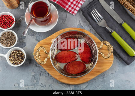 Türkisches Frühstück mit gebratenen türkischen sucuk (Bratwurst). Würstchen gebraten in Kupfer pan Stockfoto