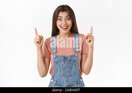 Fröhlich, wunderte sich verführerisch Mädchen teilen Big News aufgeregt, hob sie die Finger nach oben, Anzeigen top Promo und lächelte amüsiert, kühlen teilnehmen möchten. Stockfoto