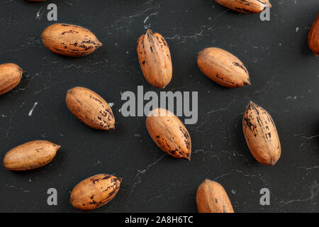 Overhead Foto-beschmutzte ganze Pekannuss (Carya illinoinensis) auf schwarzem Marmor wie Arbeiten. Stockfoto