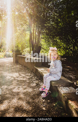 Ein kleines Mädchen erforscht die Gründe der Dunham Massey, Damwild und das Haus und die Gärten, Kind in der Landschaft UK suchen Stockfoto