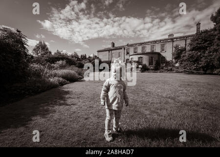 Ein kleines Mädchen erforscht die Gründe der Dunham Massey, Damwild und das Haus und die Gärten, Kind in der Landschaft UK suchen Stockfoto