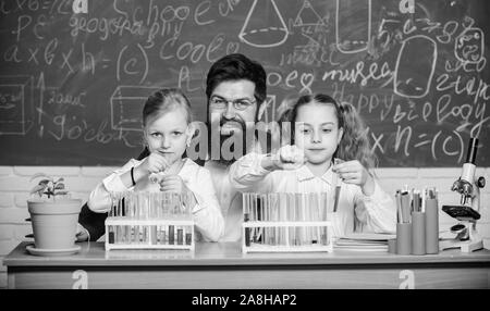 Faszinierende Biologie Lektion. Man bärtige Lehrer arbeiten mit Mikroskop und Reagenzgläser in Biologie Klassenzimmer. Schule Biologie Experiment. Erklären biolog Stockfoto