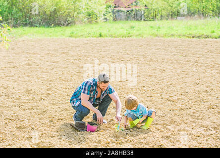 Kleiner Junge Kind helfen Vater in der Landwirtschaft. neues Leben. Böden und Düngemitteln. Vater und Sohn Blumen Pflanzen im Boden. happy Earth Day. Family Tree. Stockfoto