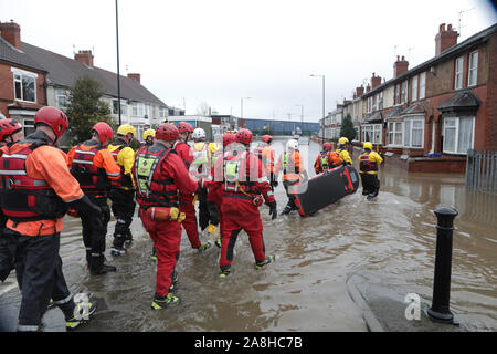 Feuerwehr und Rettungsdienste evakuieren ein behinderter Mann aus seinem Haus nach dem Hochwasser im Bentley Bereich von Doncaster nach einem Monate Niederschlag fielen auf einen Tag caausing den Don seine Banken zu verletzen. Stockfoto