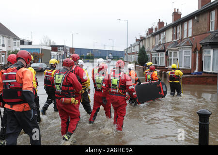 Feuerwehr und Rettungsdienste evakuieren ein behinderter Mann aus seinem Haus nach dem Hochwasser im Bentley Bereich von Doncaster nach einem Monate Niederschlag fielen auf einen Tag caausing den Don seine Banken zu verletzen. Stockfoto