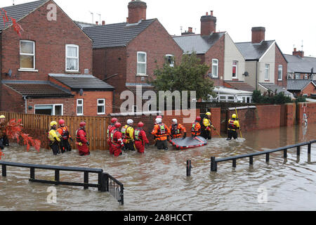 Feuerwehr und Rettungsdienste evakuieren ein behinderter Mann aus seinem Haus nach dem Hochwasser im Bentley Bereich von Doncaster nach einem Monate Niederschlag fielen auf einen Tag caausing den Don seine Banken zu verletzen. Stockfoto