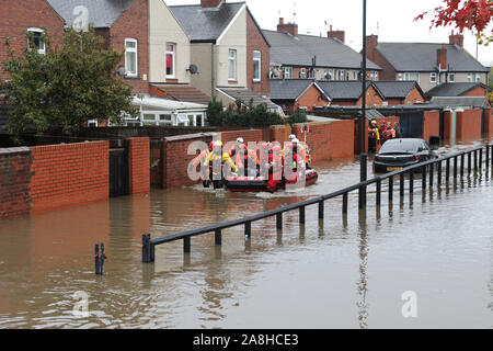 Feuerwehr und Rettungsdienste evakuieren ein behinderter Mann aus seinem Haus nach dem Hochwasser im Bentley Bereich von Doncaster nach einem Monate Niederschlag fielen auf einen Tag caausing den Don seine Banken zu verletzen. Stockfoto