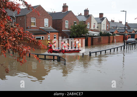 Feuerwehr und Rettungsdienste evakuieren ein behinderter Mann aus seinem Haus nach dem Hochwasser im Bentley Bereich von Doncaster nach einem Monate Niederschlag fielen auf einen Tag caausing den Don seine Banken zu verletzen. Stockfoto