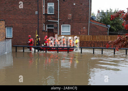 Feuerwehr und Rettungsdienste evakuieren ein behinderter Mann aus seinem Haus nach dem Hochwasser im Bentley Bereich von Doncaster nach einem Monate Niederschlag fielen auf einen Tag caausing den Don seine Banken zu verletzen. Stockfoto