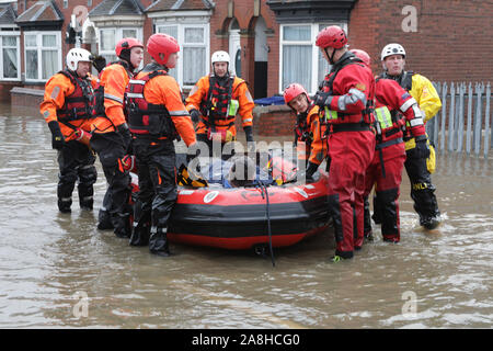 Feuerwehr und Rettungsdienste evakuieren ein behinderter Mann aus seinem Haus nach dem Hochwasser im Bentley Bereich von Doncaster nach einem Monate Niederschlag fielen auf einen Tag caausing den Don seine Banken zu verletzen. Stockfoto