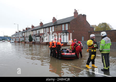 Feuerwehr und Rettungsdienste evakuieren ein behinderter Mann aus seinem Haus nach dem Hochwasser im Bentley Bereich von Doncaster nach einem Monate Niederschlag fielen auf einen Tag caausing den Don seine Banken zu verletzen. Stockfoto