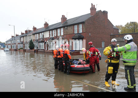 Feuerwehr und Rettungsdienste evakuieren ein behinderter Mann aus seinem Haus nach dem Hochwasser im Bentley Bereich von Doncaster nach einem Monate Niederschlag fielen auf einen Tag caausing den Don seine Banken zu verletzen. Stockfoto