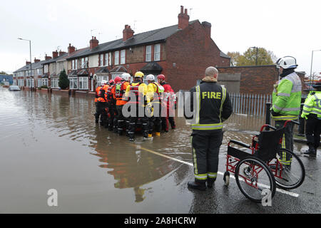 Feuerwehr und Rettungsdienste evakuieren ein behinderter Mann aus seinem Haus nach dem Hochwasser im Bentley Bereich von Doncaster nach einem Monate Niederschlag fielen auf einen Tag caausing den Don seine Banken zu verletzen. Stockfoto