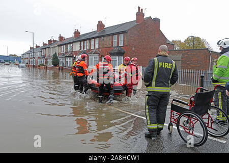 Feuerwehr und Rettungsdienste evakuieren ein behinderter Mann aus seinem Haus nach dem Hochwasser im Bentley Bereich von Doncaster nach einem Monate Niederschlag fielen auf einen Tag caausing den Don seine Banken zu verletzen. Stockfoto