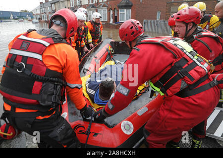 Feuerwehr und Rettungsdienste evakuieren ein behinderter Mann aus seinem Haus nach dem Hochwasser im Bentley Bereich von Doncaster nach einem Monate Niederschlag fielen auf einen Tag caausing den Don seine Banken zu verletzen. Stockfoto