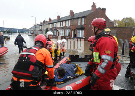 Feuerwehr und Rettungsdienste evakuieren ein behinderter Mann aus seinem Haus nach dem Hochwasser im Bentley Bereich von Doncaster nach einem Monate Niederschlag fielen auf einen Tag caausing den Don seine Banken zu verletzen. Stockfoto