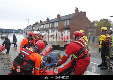 Feuerwehr und Rettungsdienste evakuieren ein behinderter Mann aus seinem Haus nach dem Hochwasser im Bentley Bereich von Doncaster nach einem Monate Niederschlag fielen auf einen Tag caausing den Don seine Banken zu verletzen. Stockfoto