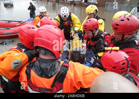 Feuerwehr und Rettungsdienste evakuieren ein behinderter Mann aus seinem Haus nach dem Hochwasser im Bentley Bereich von Doncaster nach einem Monate Niederschlag fielen auf einen Tag caausing den Don seine Banken zu verletzen. Stockfoto