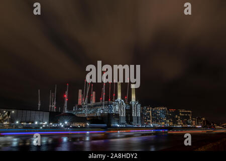 Battersea Power Station in der Nacht mit der roten Lichter von viele Kräne und leichte Spuren von Booten entlang der Themse Stockfoto
