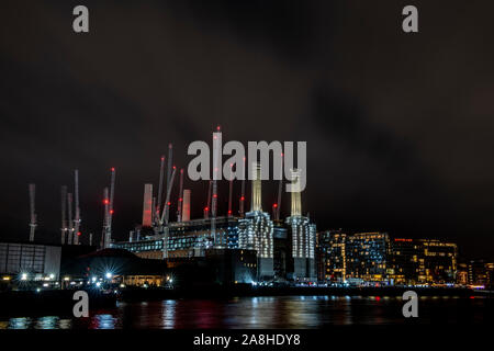 Battersea Power Station in der Nacht mit der roten Lichter von viele Kräne und leichte Spuren von Booten entlang der Themse Stockfoto