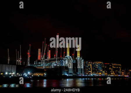Battersea Power Station in der Nacht mit der roten Lichter von viele Kräne und leichte Spuren von Booten entlang der Themse Stockfoto