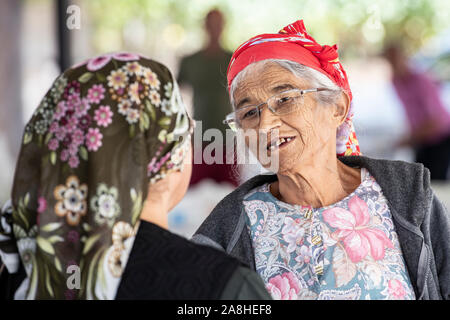 Eine Dame mit fehlenden Zähnen und ein rotes Kopftuch spricht mit ihrem Freund in einem Dorf in der Türkei Stockfoto