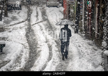 Kaschmir, Indien. 09 Nov, 2019. Ein Bewohner Spaziergänge entlang der schneebedeckten Straße halten Sie einen Regenschirm während Der starke Schneefall in Kaschmir. Mindestens sieben Menschen in verschiedenen Vorfälle starb an vielen Orten des Tals während Jahreszeiten ersten Schneefall. Eine meteorologische Abteilung hat trockenes Wetter in der Region für die nächste Woche vorhergesagt. Credit: SOPA Images Limited/Alamy leben Nachrichten Stockfoto